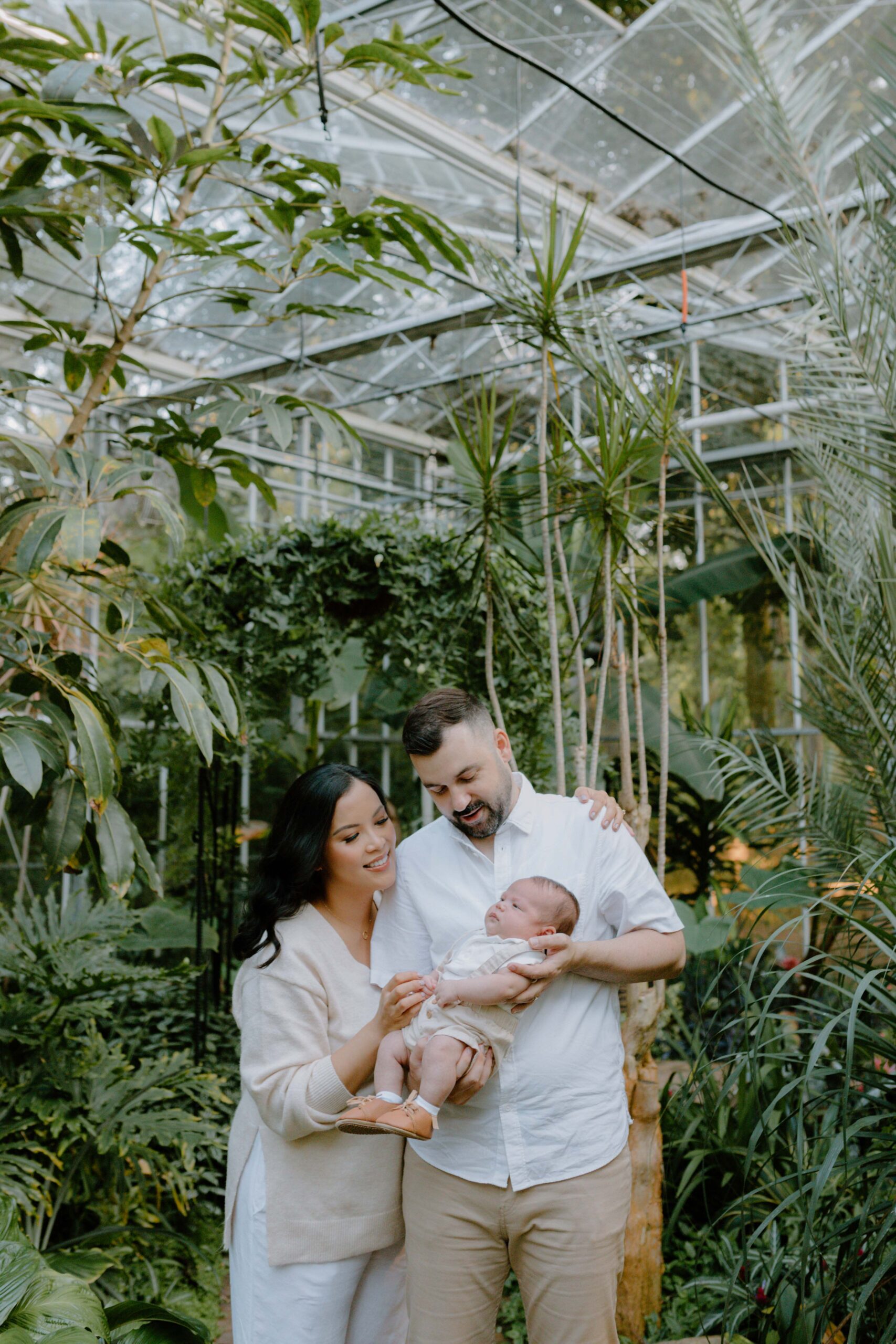 Mom and dad hold newborn baby in a garden