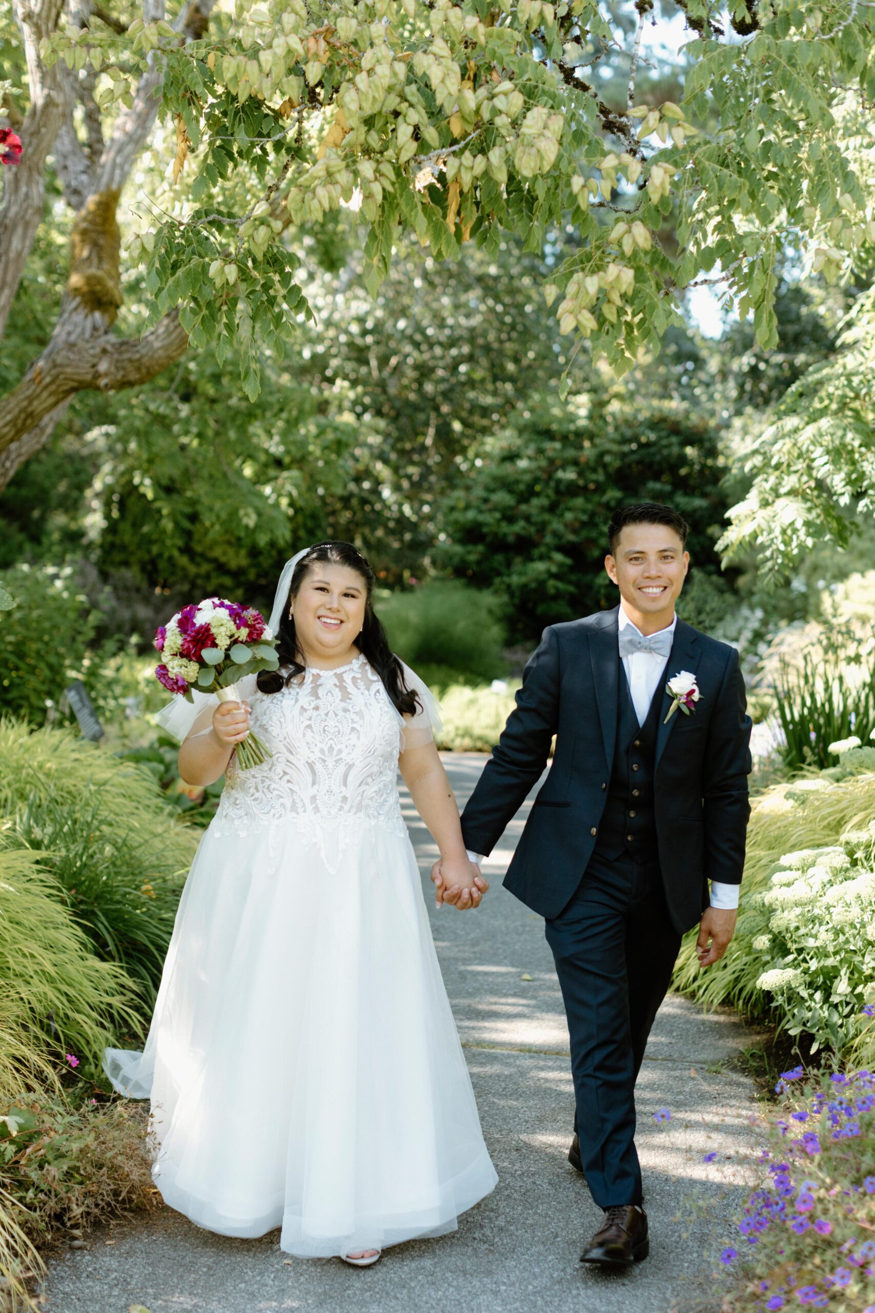 Bride and groom are standing in a garden, smiling