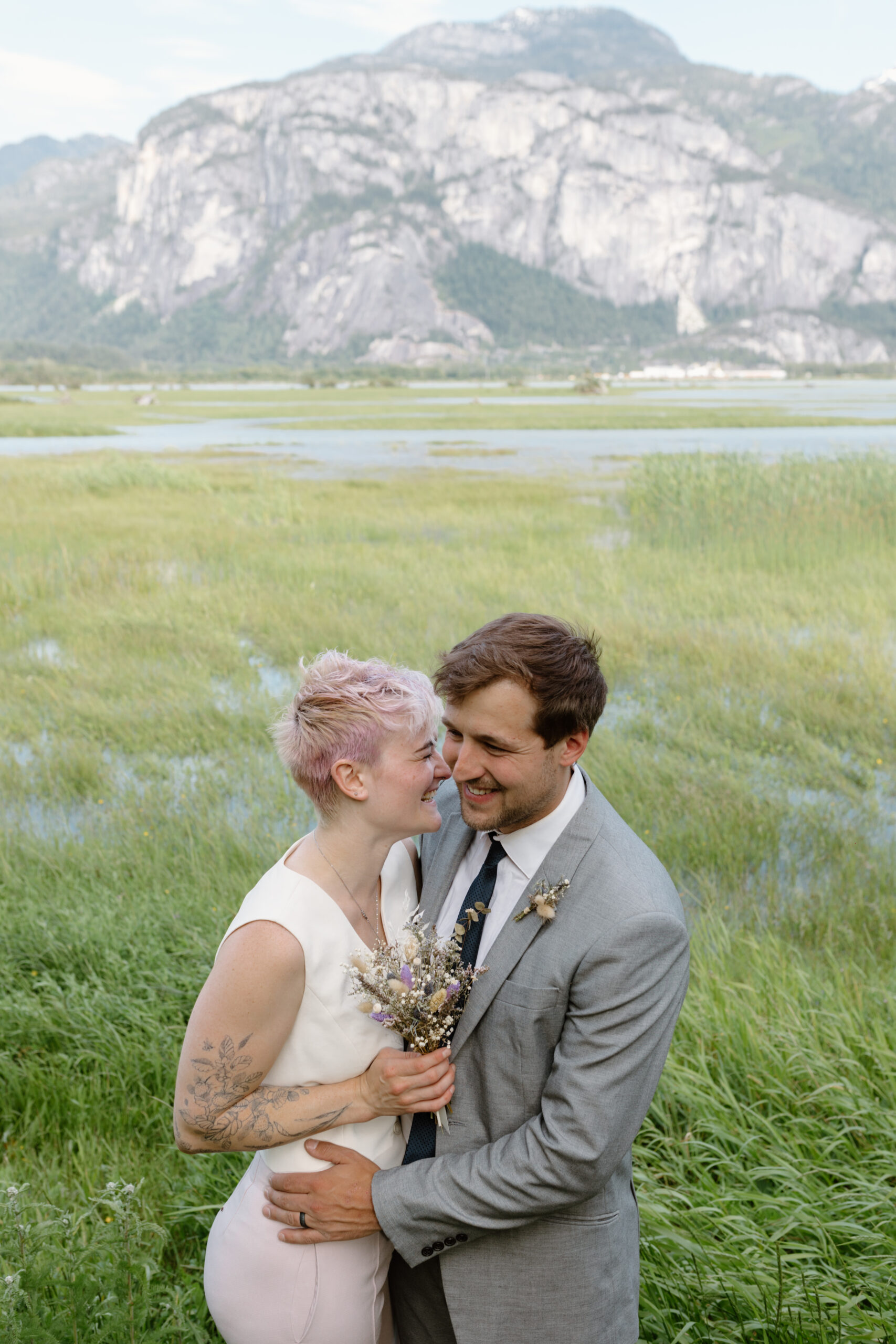 Man and woman hug with the backdrop of a marsh with mountains