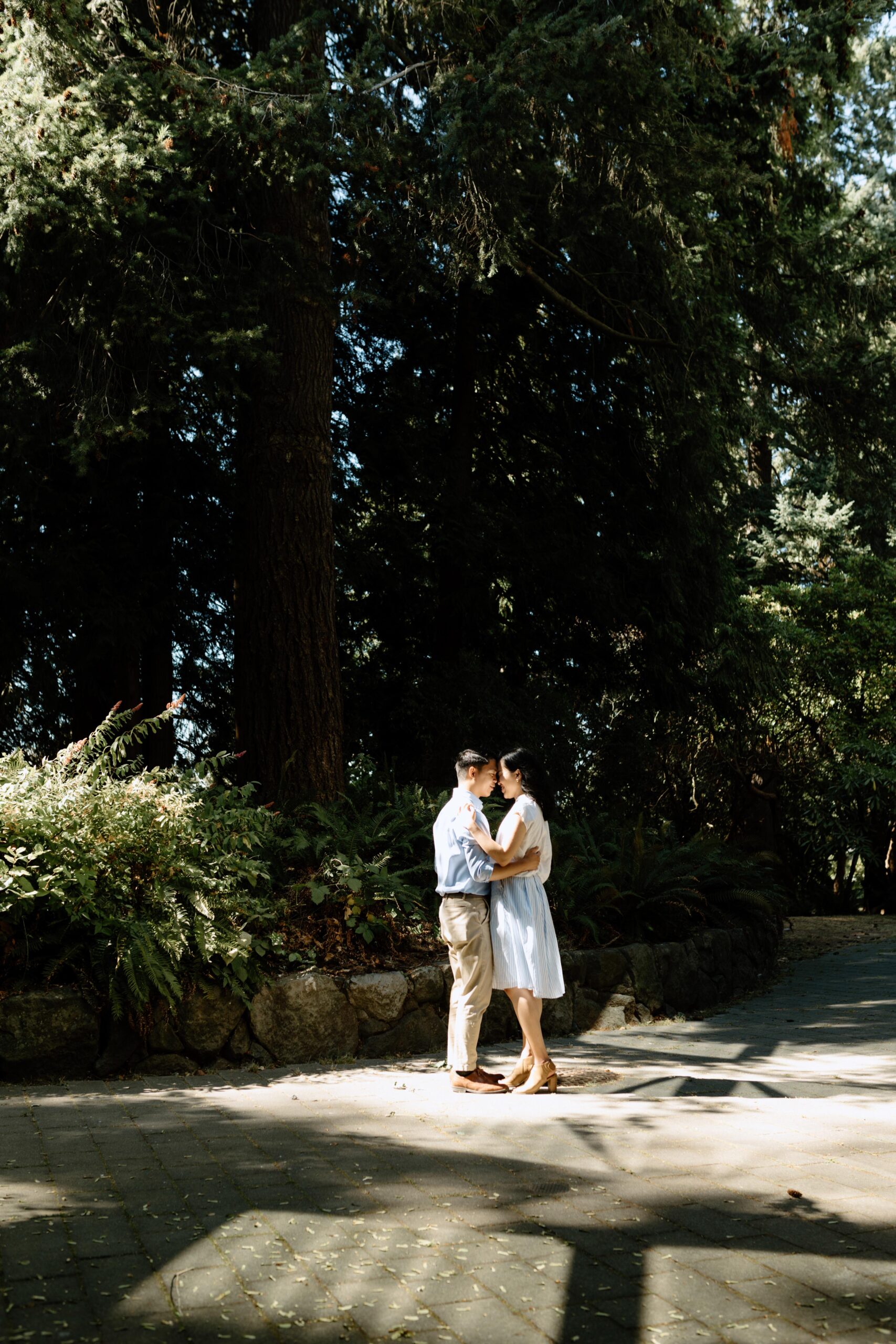 Man and woman slow dance in a forest in a patch of light