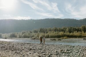 couple walking with the view of a river and mountains in the background