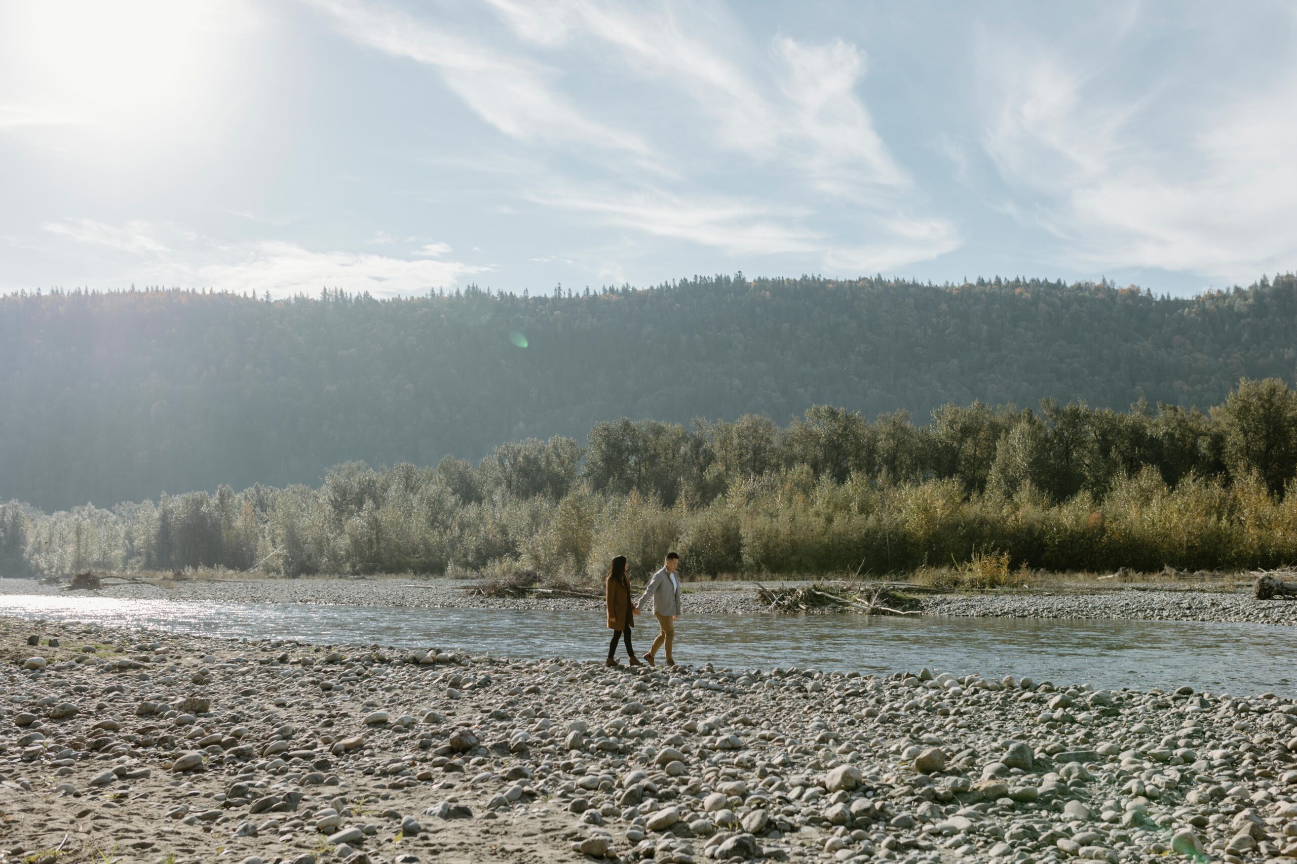 couple walking with the view of a river and mountains in the background